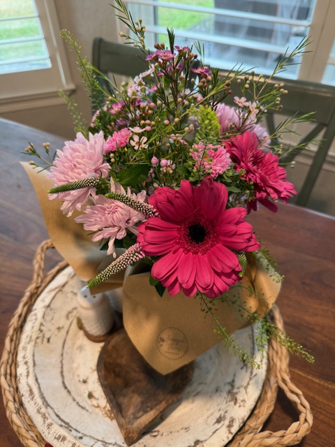Pink gerbera daisy bouquet wrapped in kraft paper with a Journeycake Flowers sticker